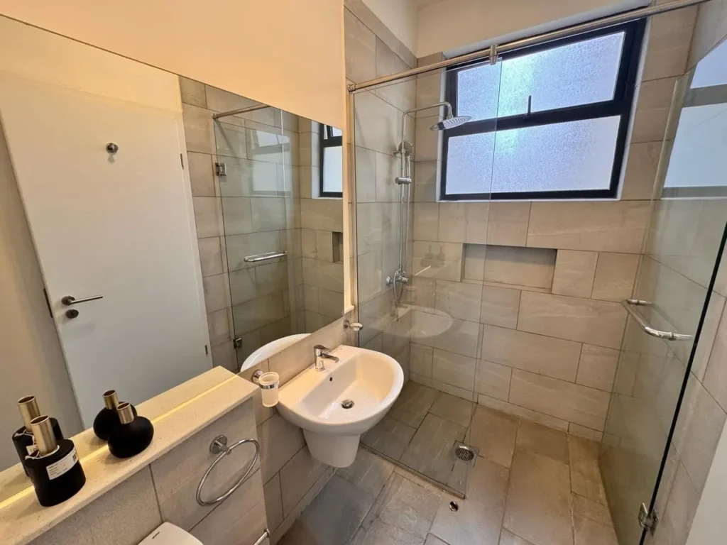 Contemporary bathroom with glass shower enclosure and pedestal sink at Rumaisa Residency, Riverside Drive Nairobi.