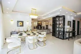 Elegant dining area at J & M Palms Residence Nairobi featuring gold-accented chairs, designer chandelier lighting and open-plan layout.