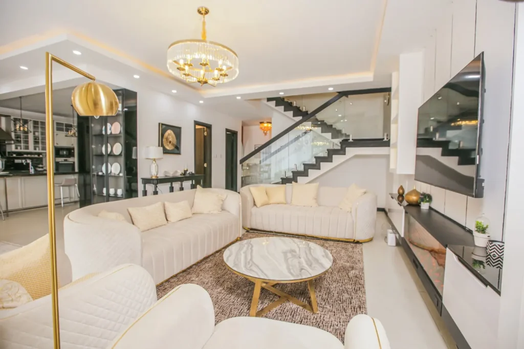 Luxury modern living room at J & M Palms Residence Nairobi featuring curved designer sofas, chandelier lighting, glass staircase and premium finishes.